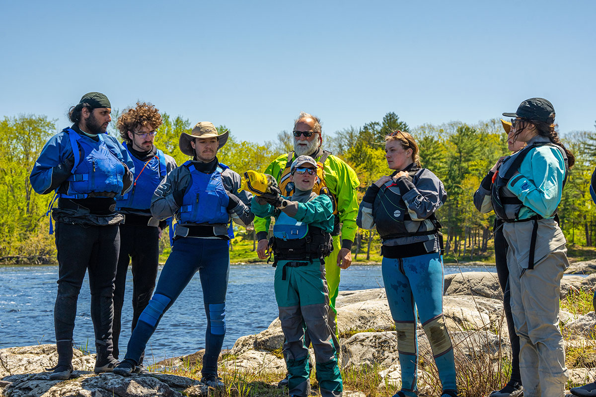 A group of people standing on rocks in front of a body of water