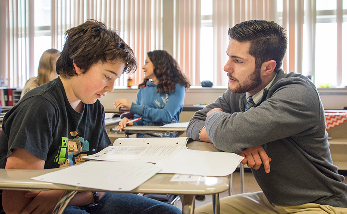 Teacher and student at a desk talking about school work