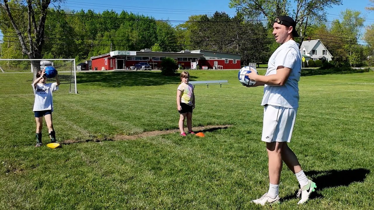 A photo of a soccer coach and kids on a field