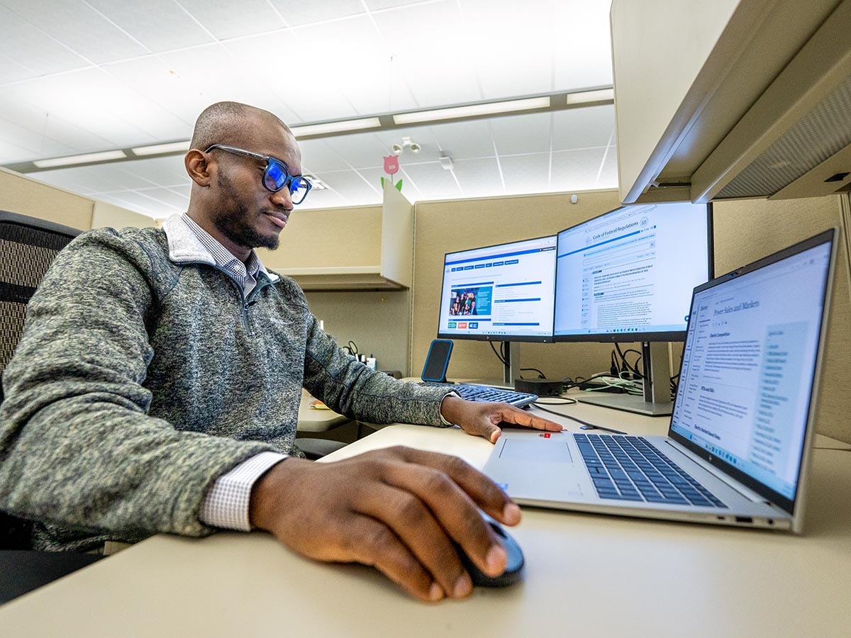 A photo of a UMaine student working at a desk with a computer