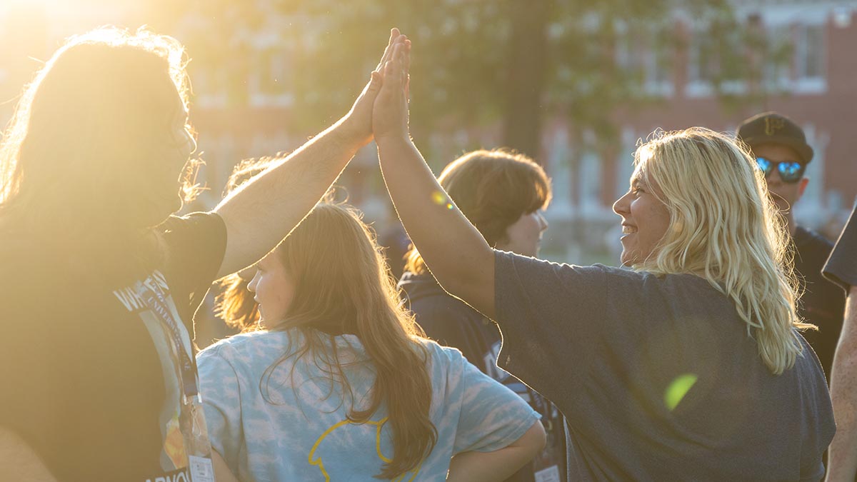 A photo of two people high fiving on UMaine's Mall during Orientation