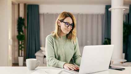 A happy person typing on laptop and working online from home.
