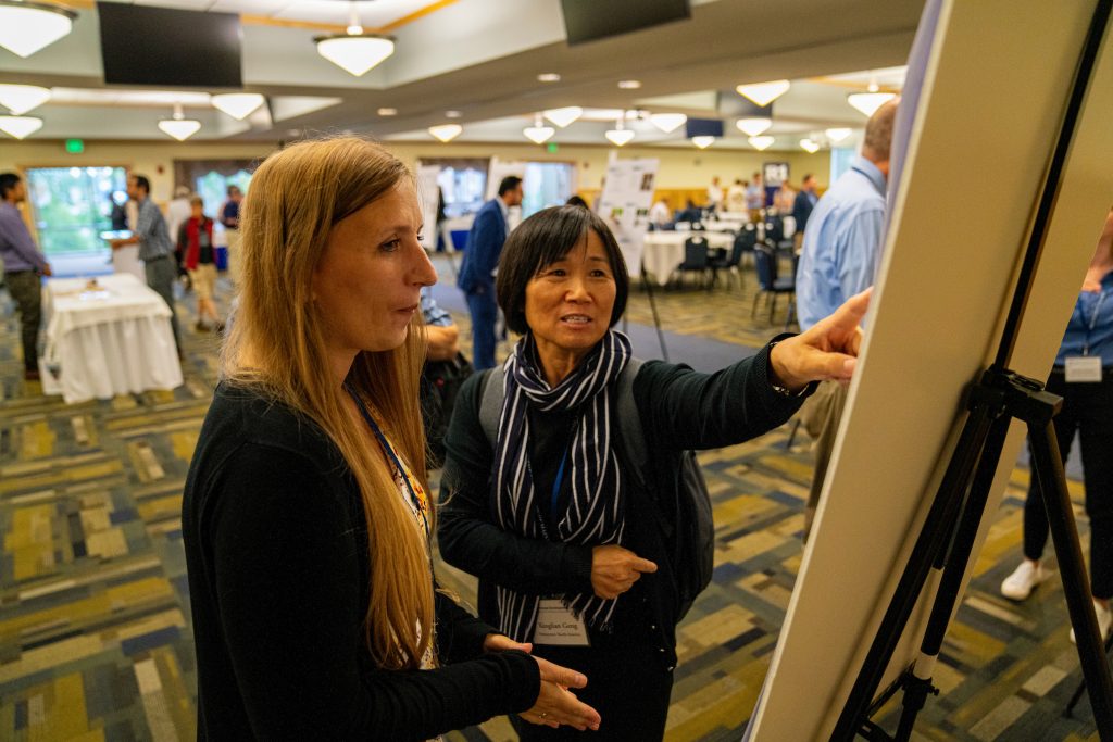 a photo of a woman explaining a poster at a conference in Wells Conference Center