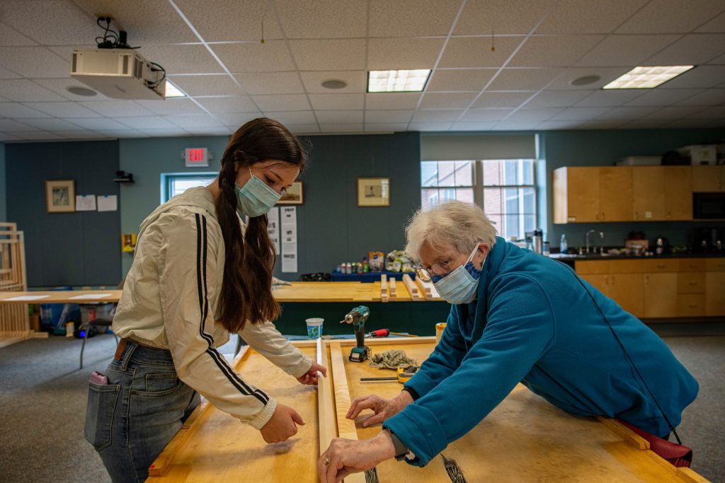 photo of an older woman and younger woman building a window insulation insert