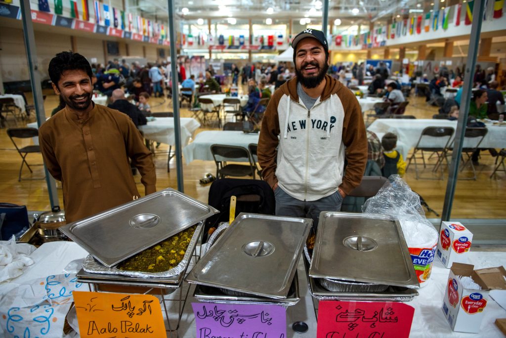 Two men standing behind a table with food offered at culturefest November 2018