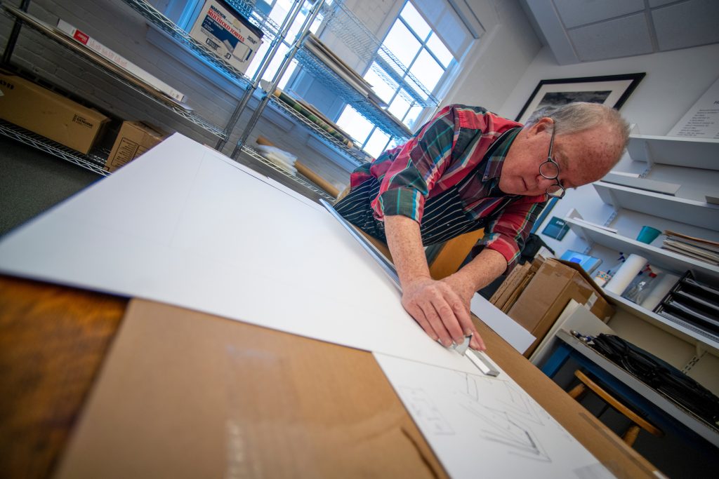 photo of art professor James Linehan demonstrating matte cutting and framing for a student