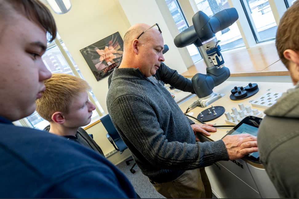 Image of Advanced Manufacturing Center director controlling interactive co-bot in a high-school workshop