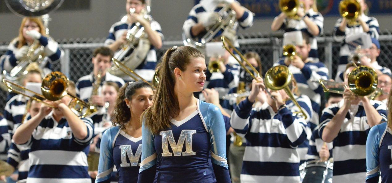 member of the dance team in the foreground, pep band in the background