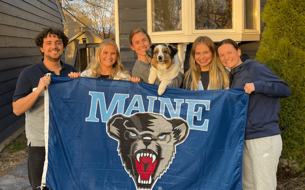 students and faculty holding a Maine flag