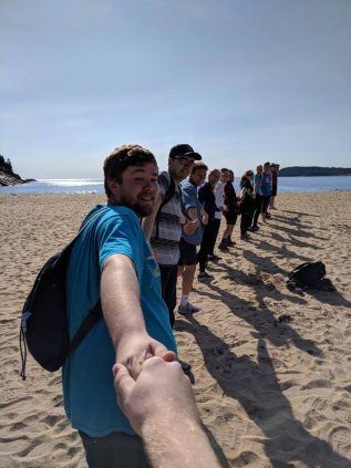 People standing on a beach hoding hands