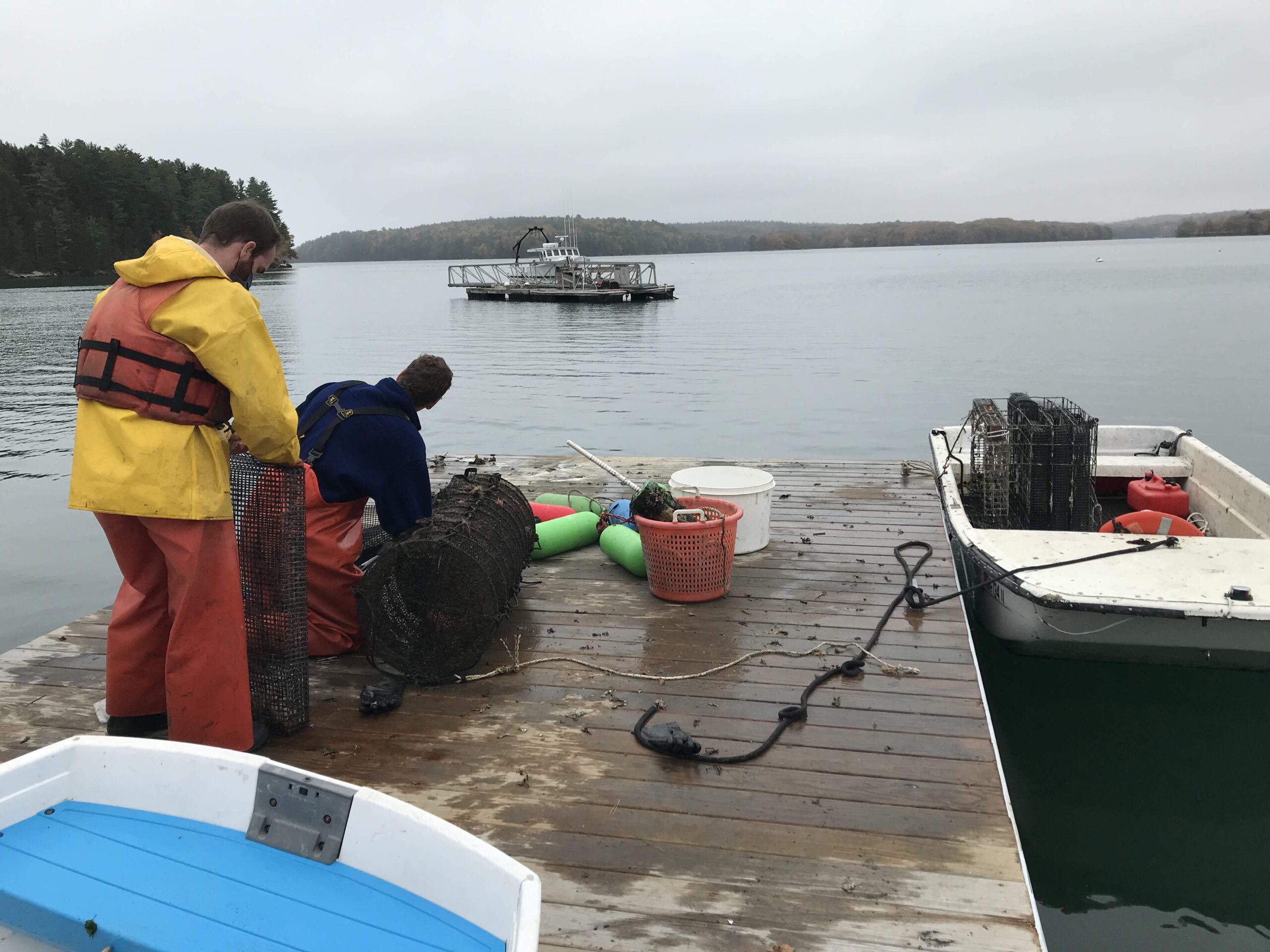 Two students work on aquaculture bags on dock