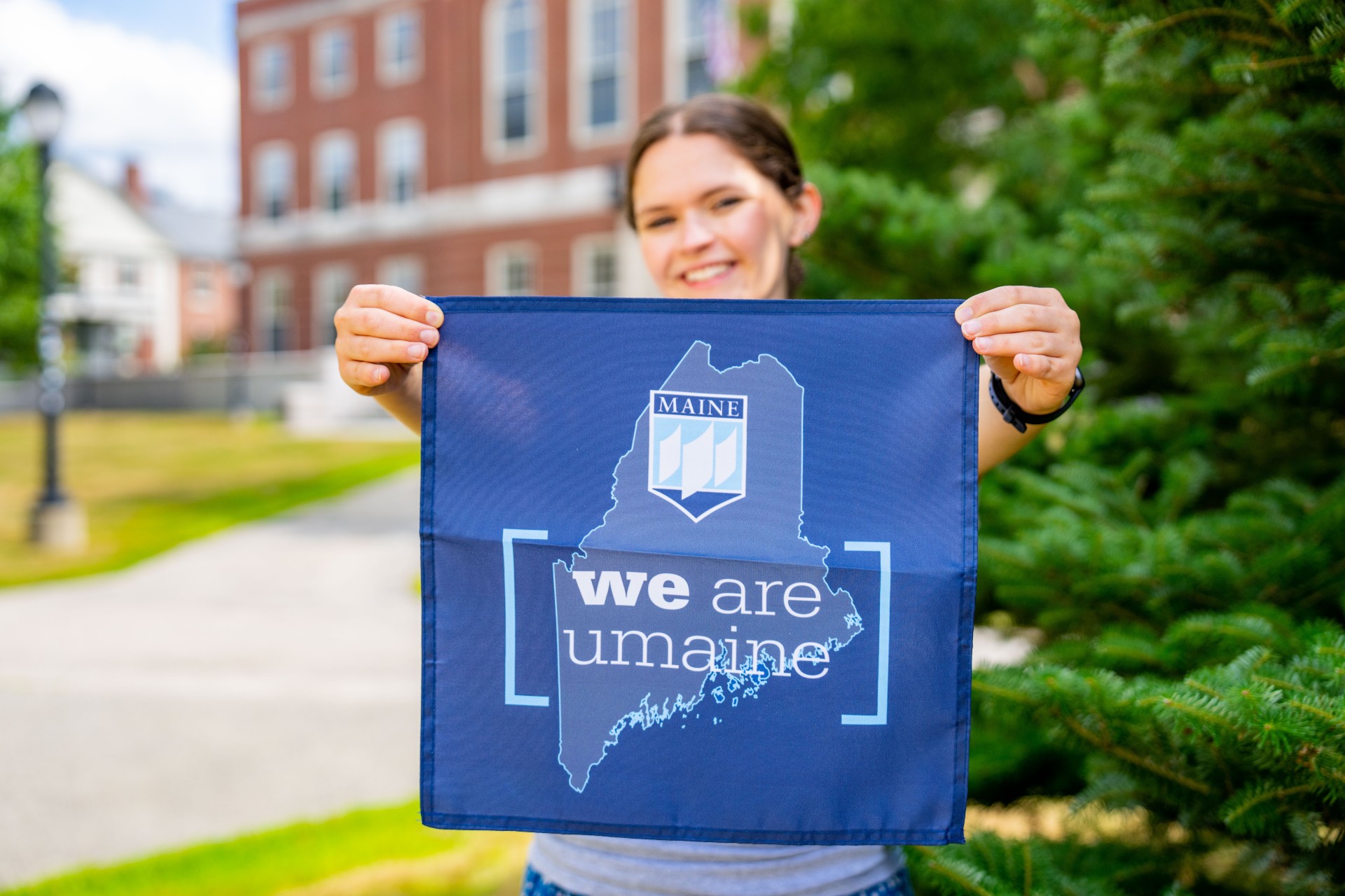A photo of a woman holding a "we are umaine flag"