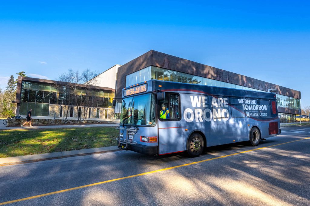 A photo of a bus wrapped with a UMaine design