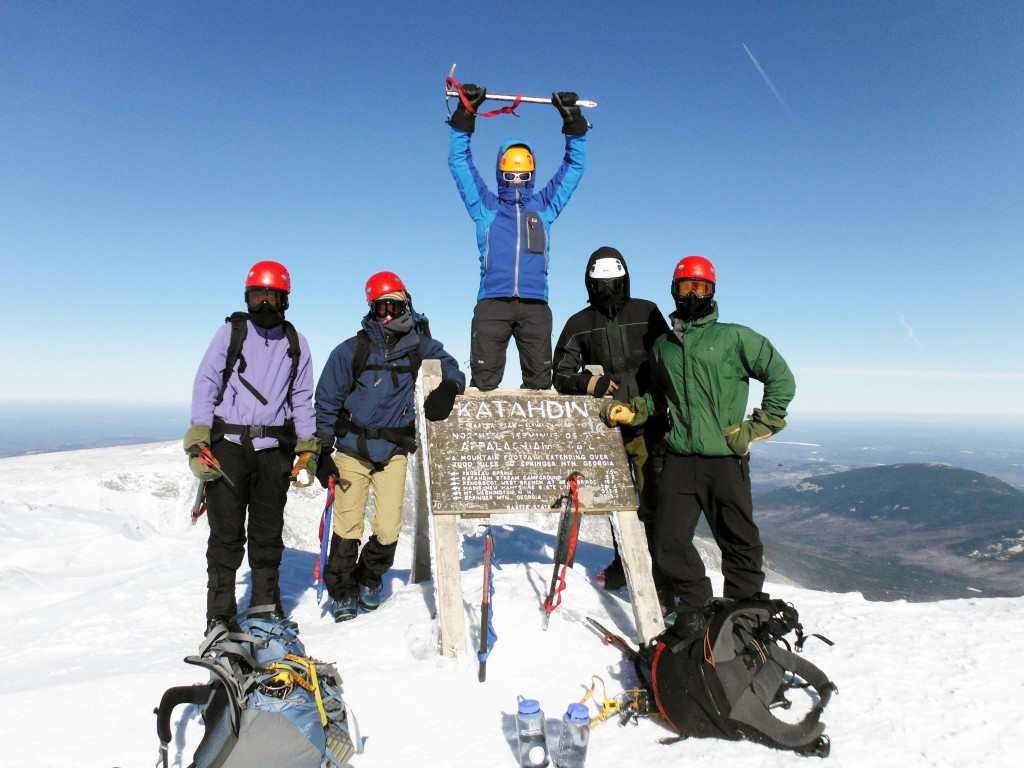 A group of team members celebrating at the top of Mount Katahdin in the winter.
