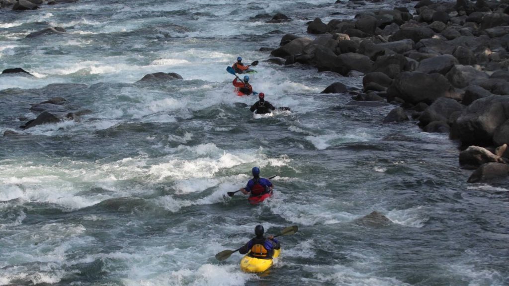 Students in kayaks navigate rapids