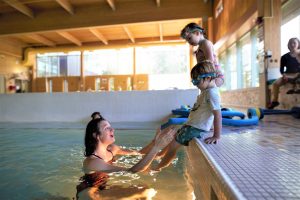 children on pool edge with instructor catching