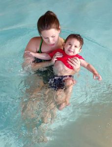 instructor with toddler floating on back