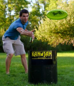 Young adult throws frisbee over Kan Jam game