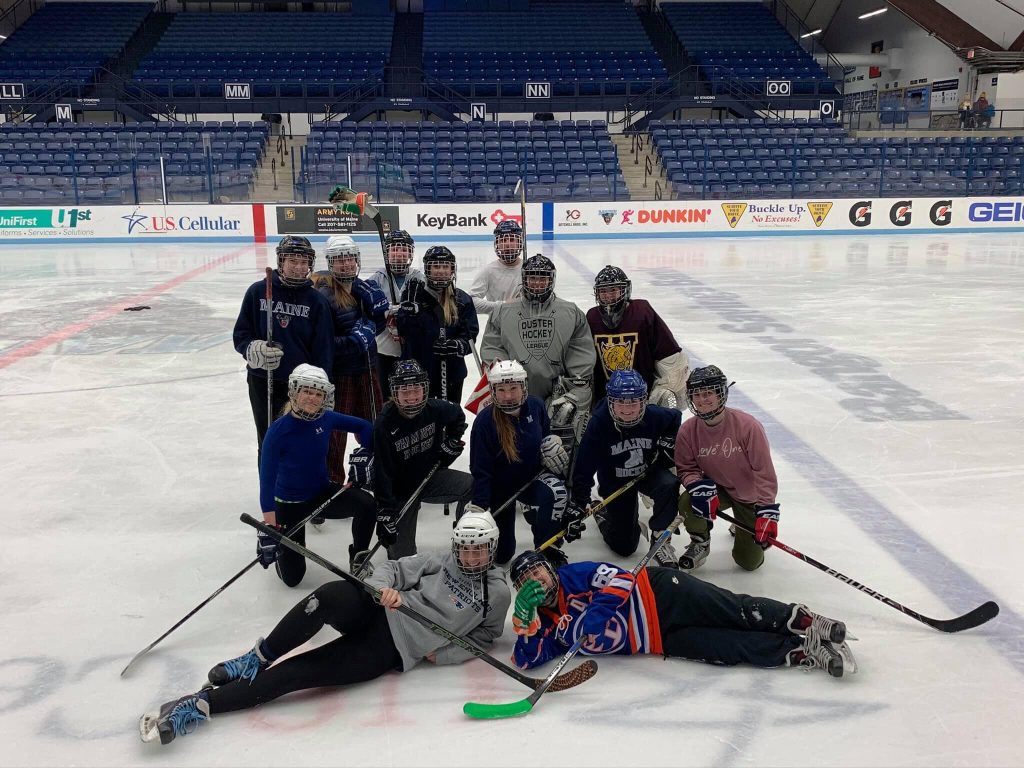 The Women's Ice Hockey team posing for a group photo on the ice of Alfond Arena