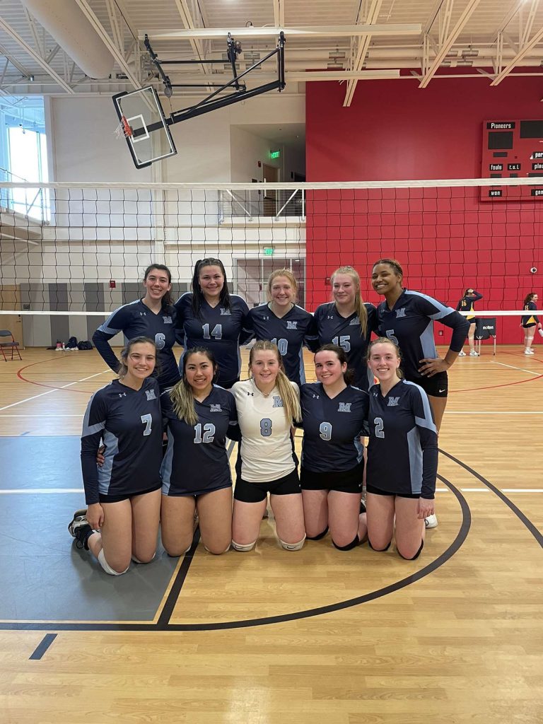 A 2022 photo of the womens volleyball team assembled on the indoor court