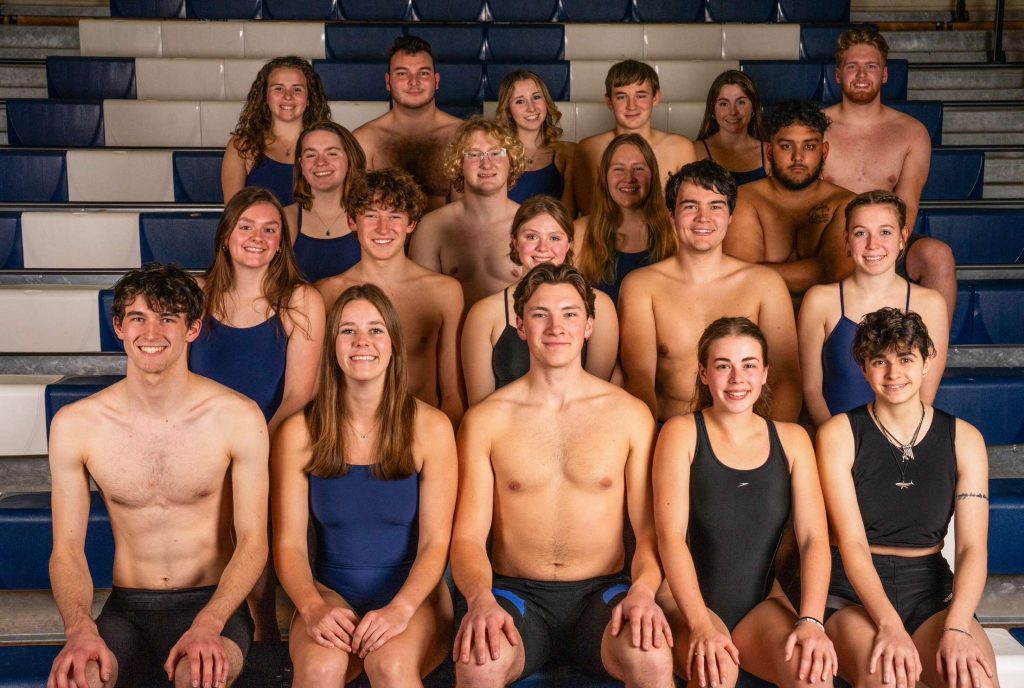 Group photo of the UMaine Swim Club in their swimsuits, seated in bleachers