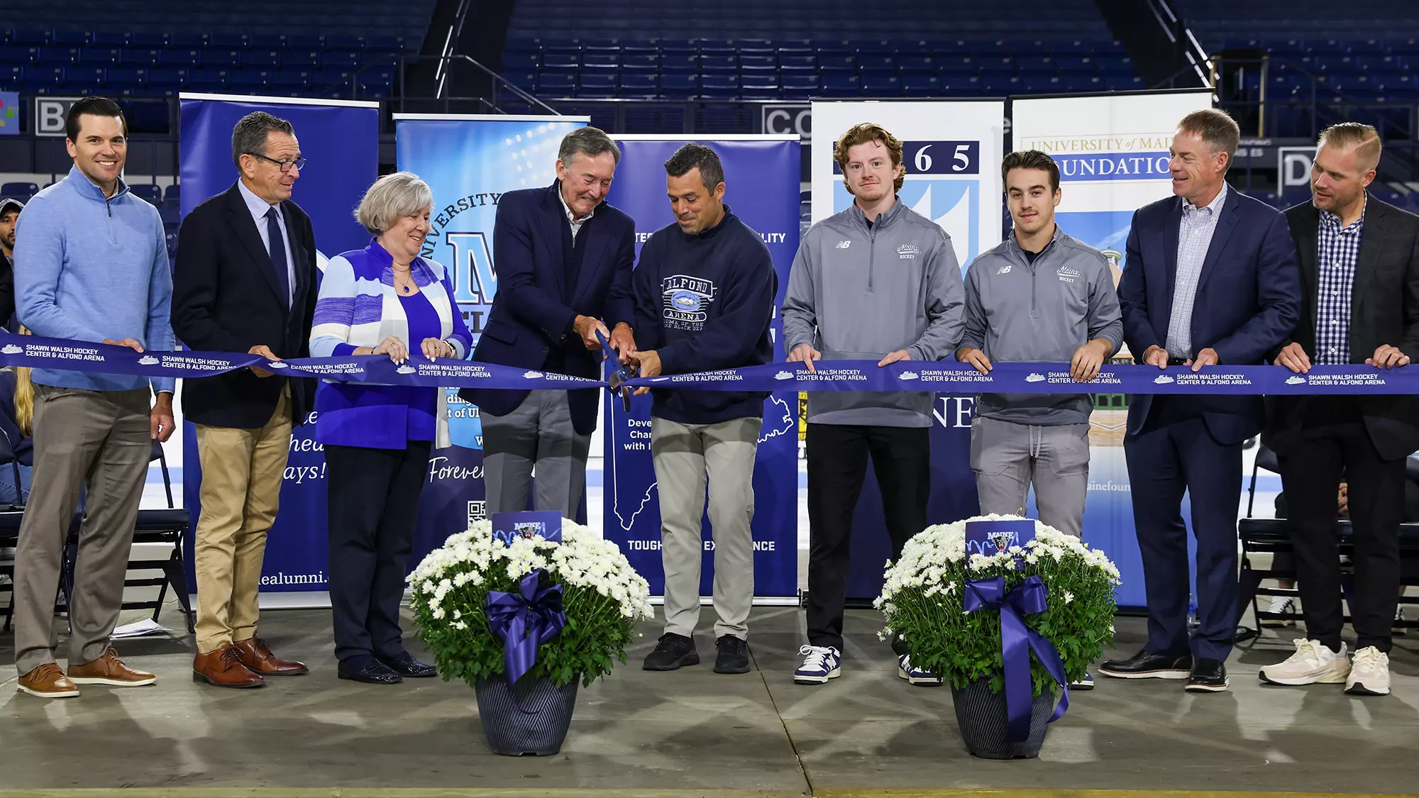 People standing in a line for the ribbon cutting for the Shawn Walsh Hockey Center & Alfond Arena renovations