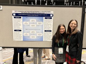 Caroline Kelberman and Eleanor Schuttenberg standing with a poster at the ABCT conferece