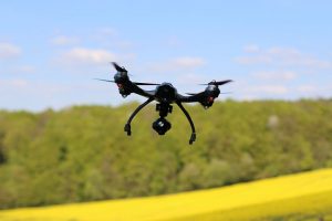 drone flying above a green forest with blue skies and clouds on the horizon