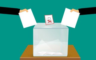 A cartoon image of a ballot box with two hands holding ballots on either side of th ebox