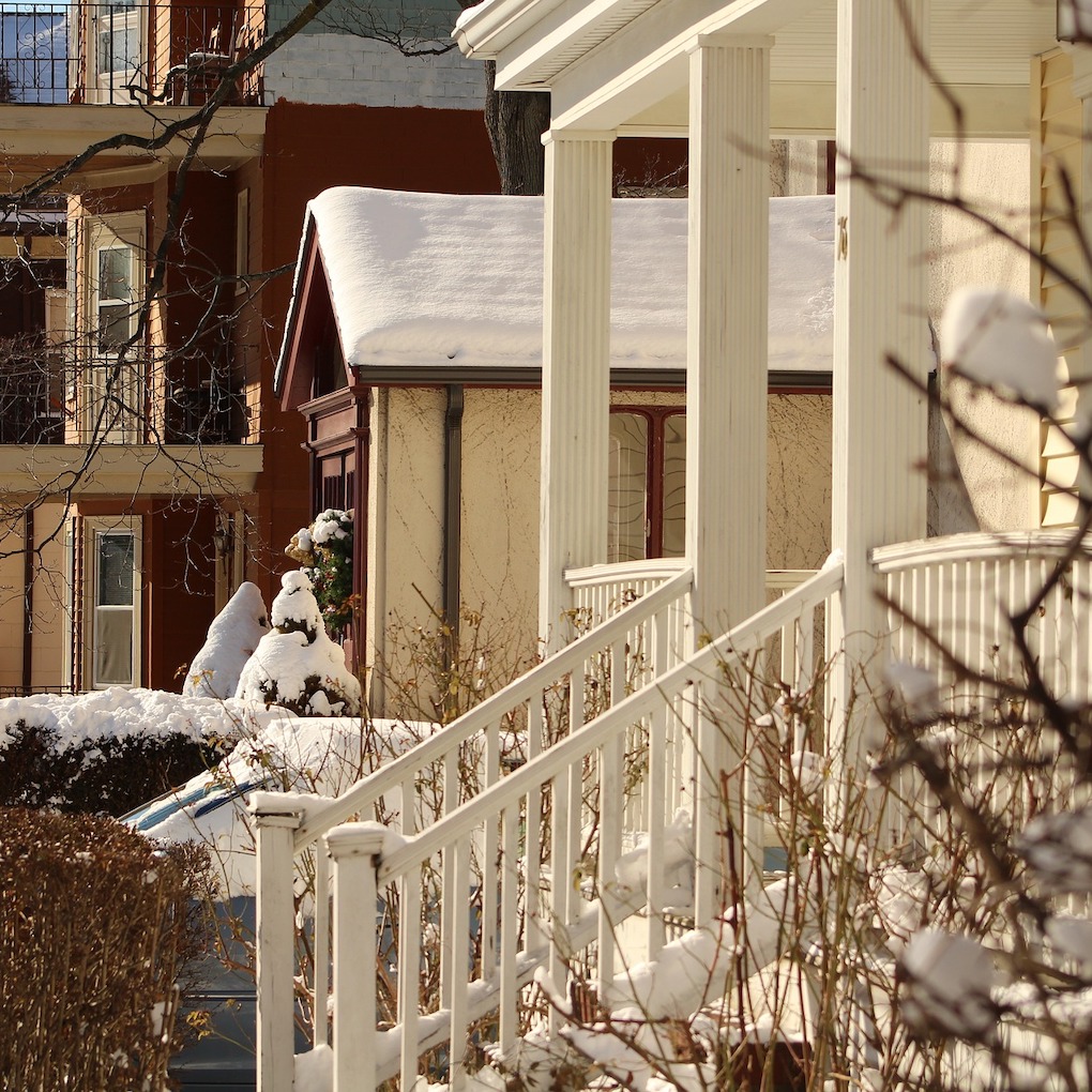 Porch of a New England style house, with in the background a small private house and apartment building in Somerville, Massachusetts