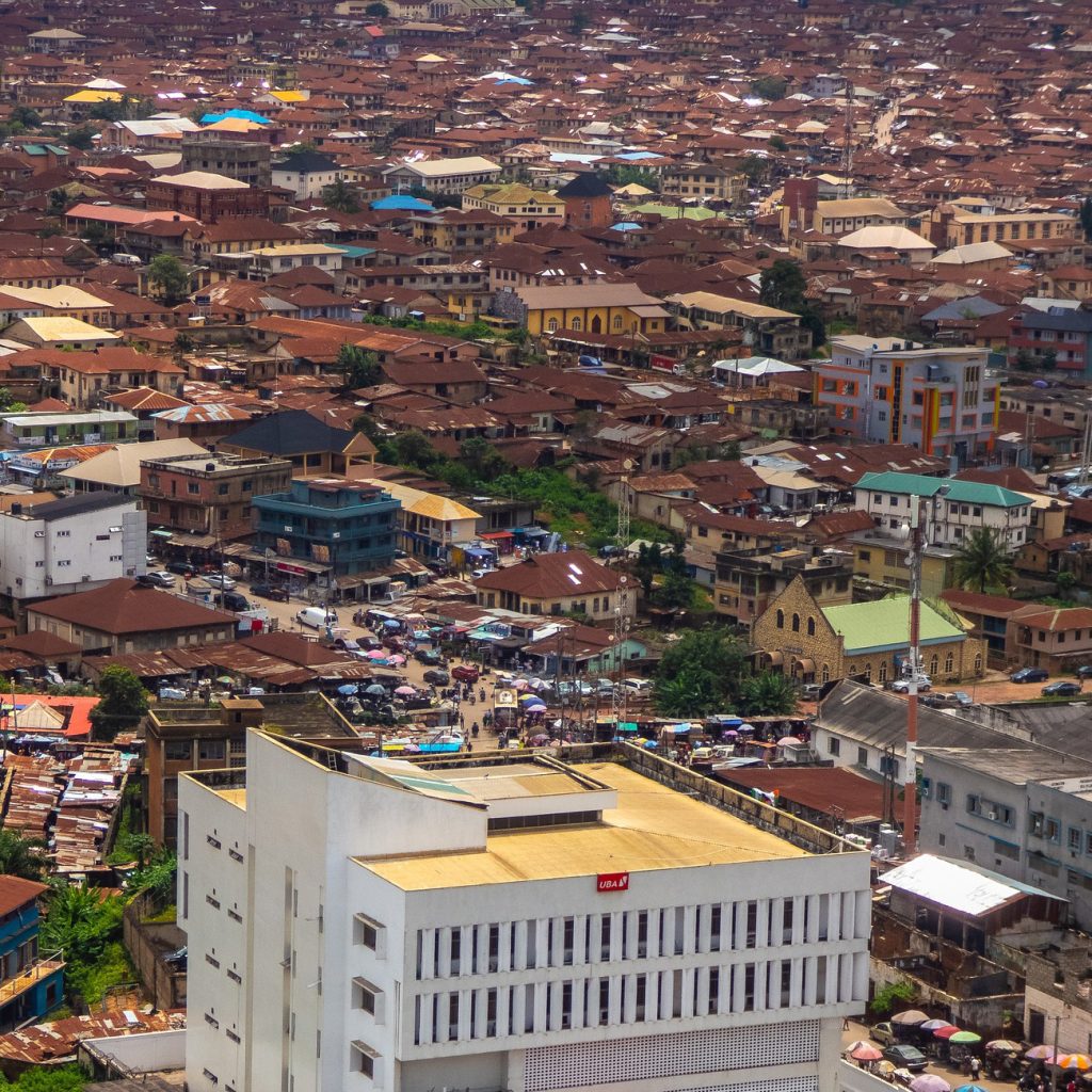 Aerial view of Ibadan, Nigeria, with a large corporate building in the forefront, and a commercial area and medium to low rise residential buildings behind it.