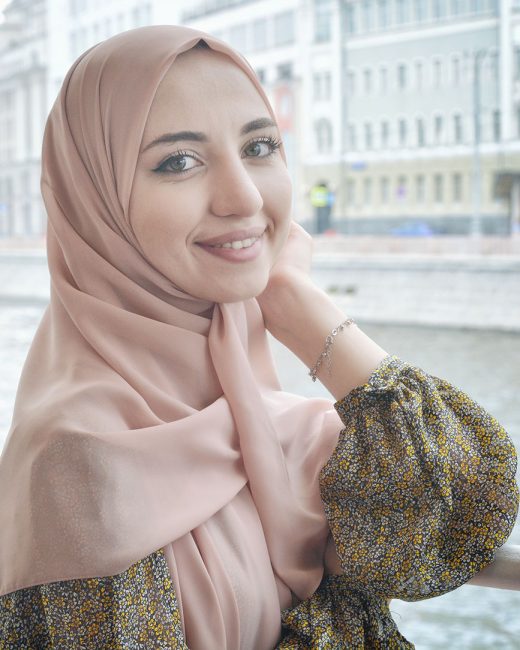 Young fair skinned woman wearing a headscarf (hijab) smiling gently at the camera