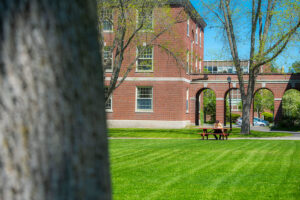 A student sits at a picnic table; Stevens Hall is in the background