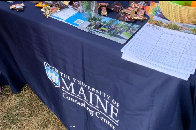 image of counseling center table with table cloth, hand outs, and candy on top of the table.