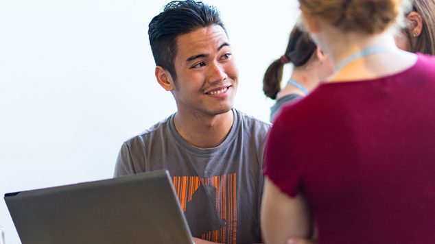 Technology support person helping to students on laptop