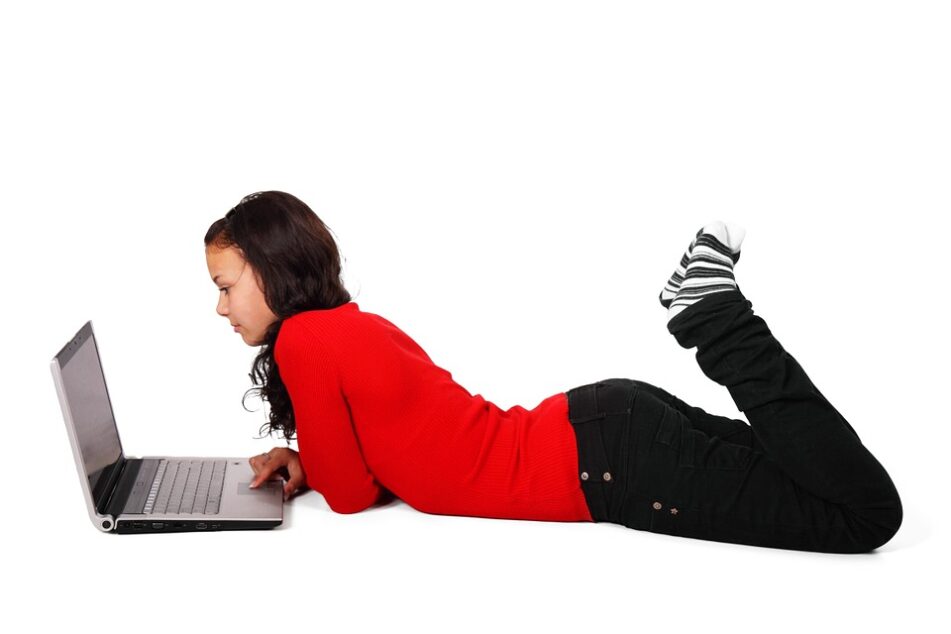 Student lying on stomach, looking at a laptop