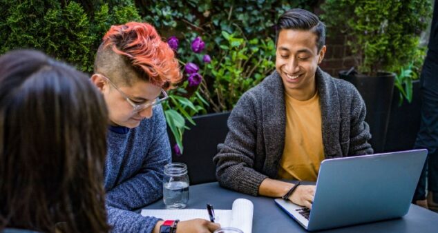 Students with paper and laptop sitting at a table