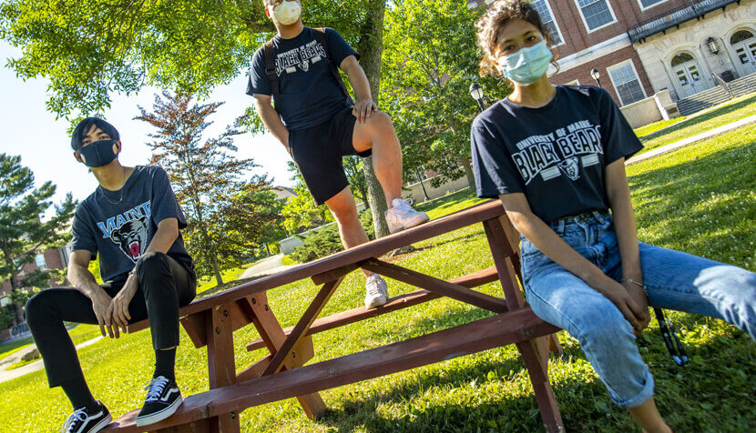 Students at UM sitting at a picnic table wearing masks