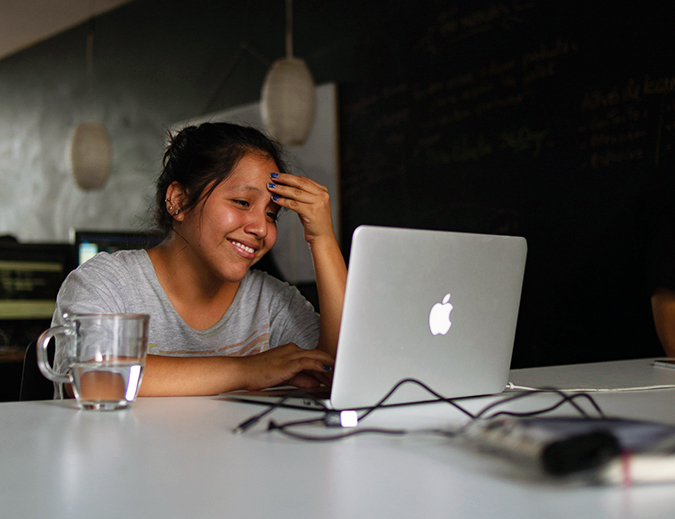 Person sitting at laptop smiling with hand on head