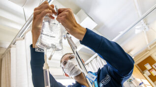 nursing student attaching an iv fluid bag