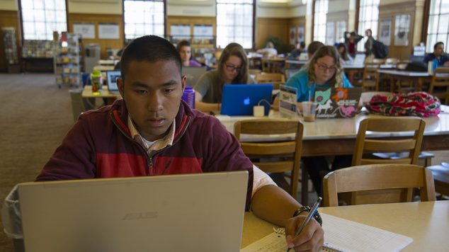 Students look at laptops in the library.