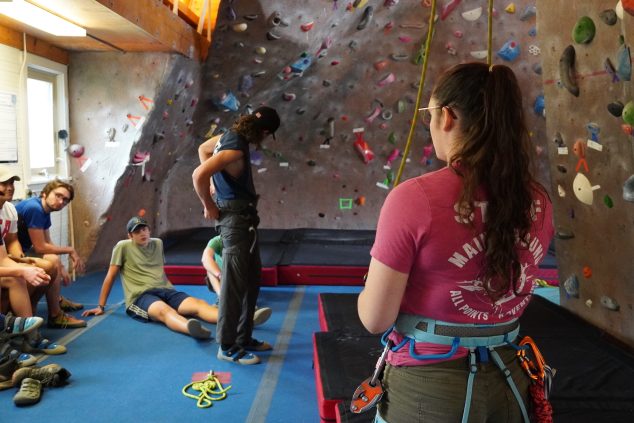 Students receive instructions for climbing wall