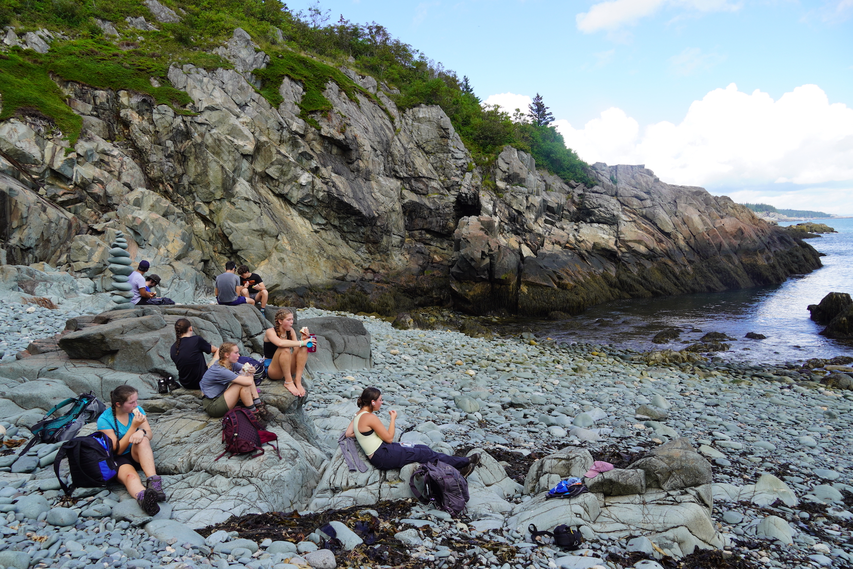 Students eat lunch sitting on rocky Maine beach