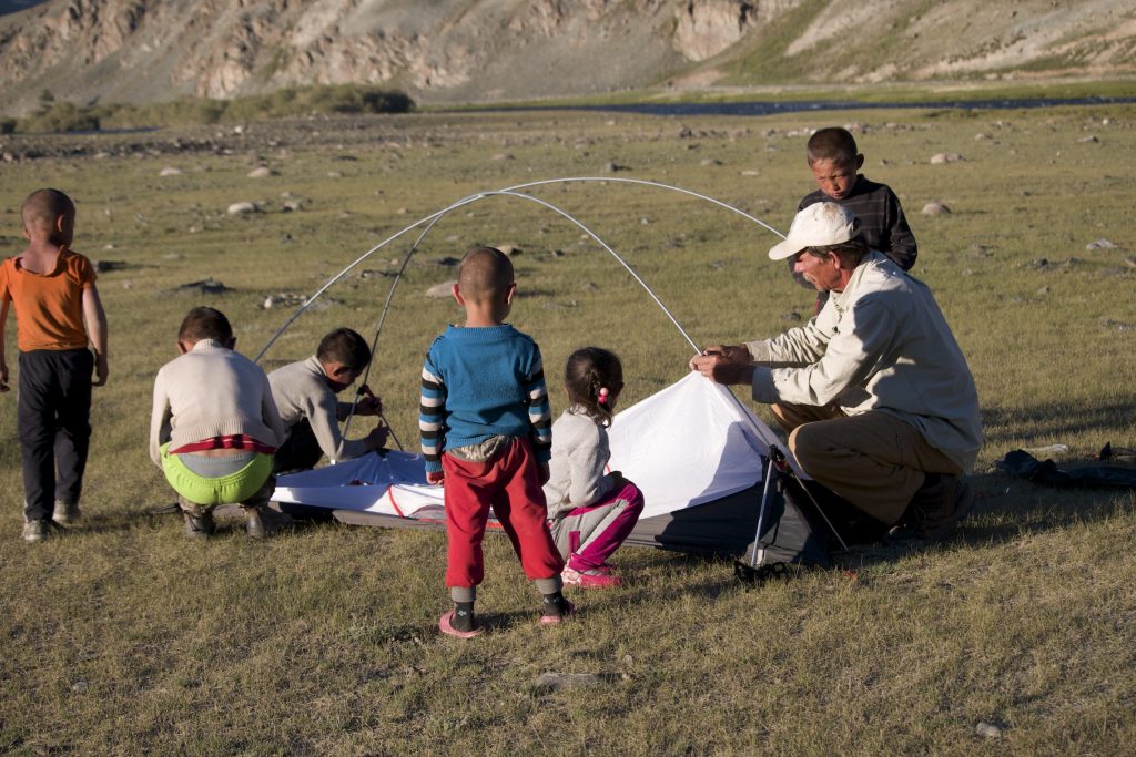 Young Khazak children help Dave Putnam set up his tent