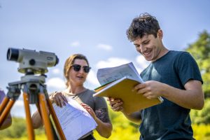 Student and teaching assistant using surveying equipment