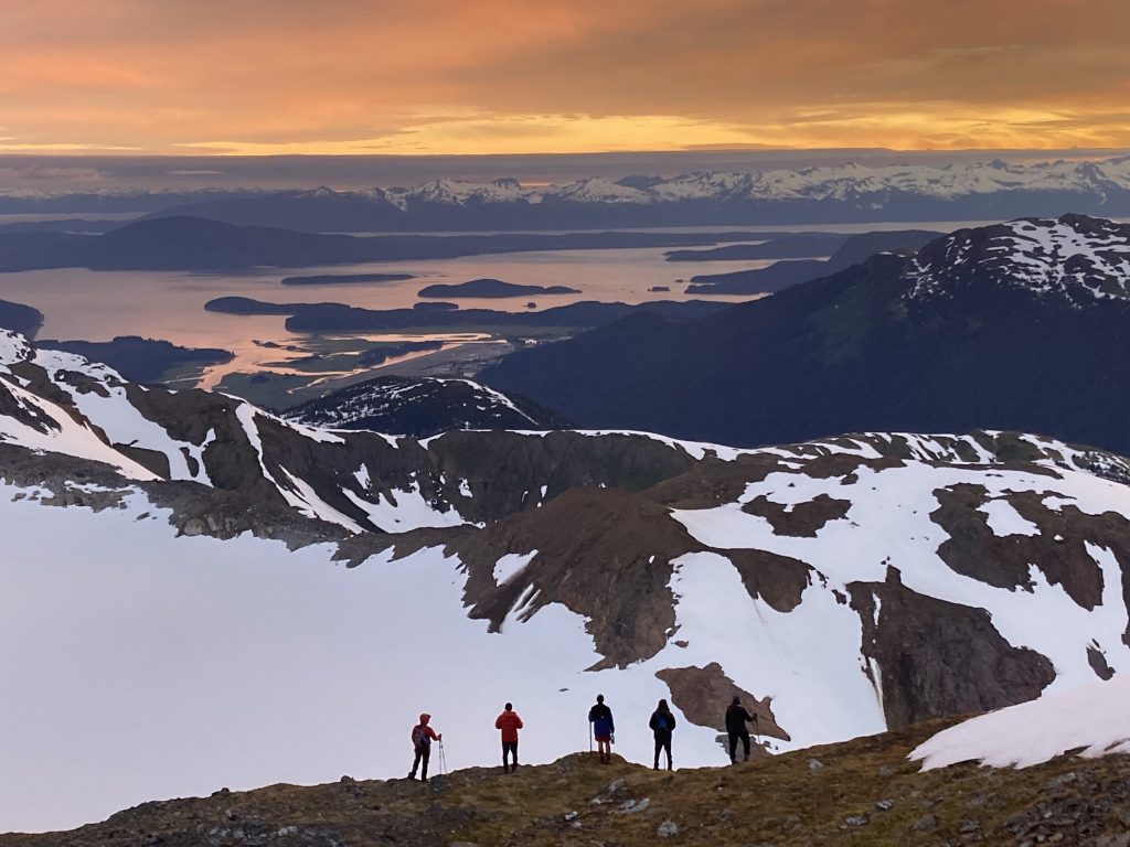 Panoramic shot of students walking with the sunset over the mountain valley in the background
