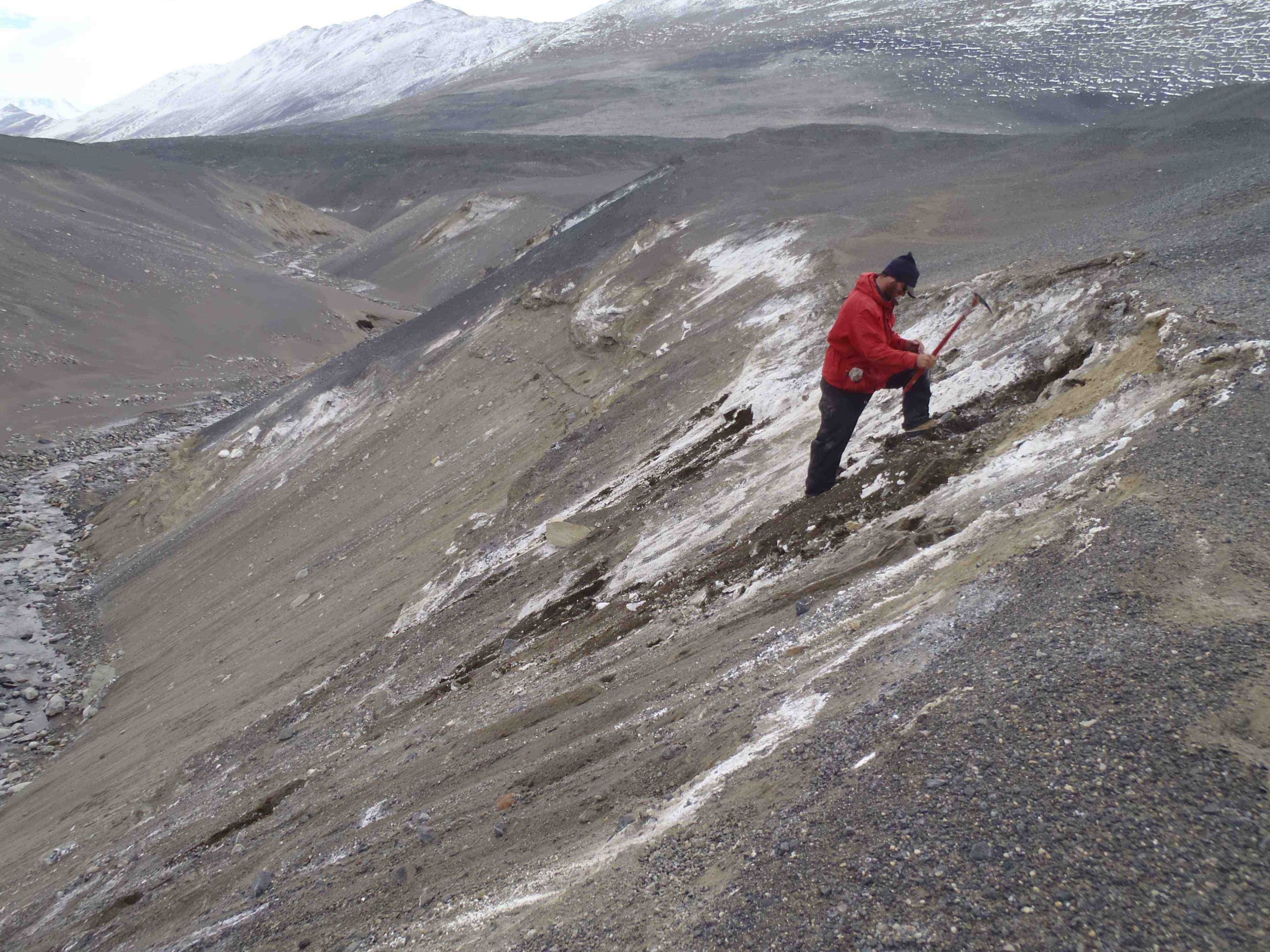 Researcher cleans a section near the mouth of Miers Valley, standing on the slope with an ice pick