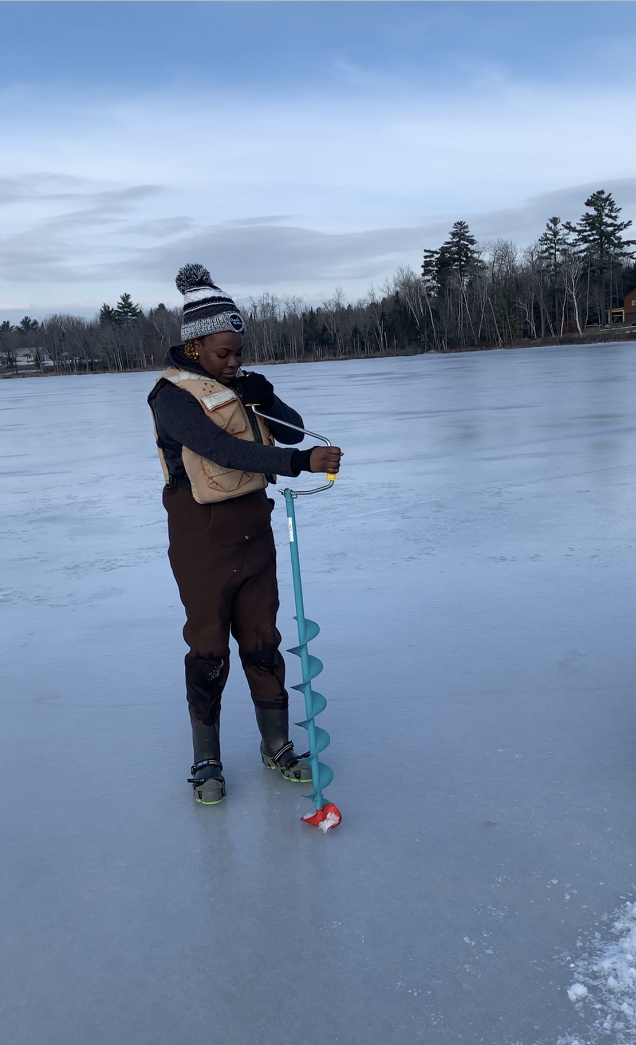 Deborah Alademehin drilling a hole in the ice