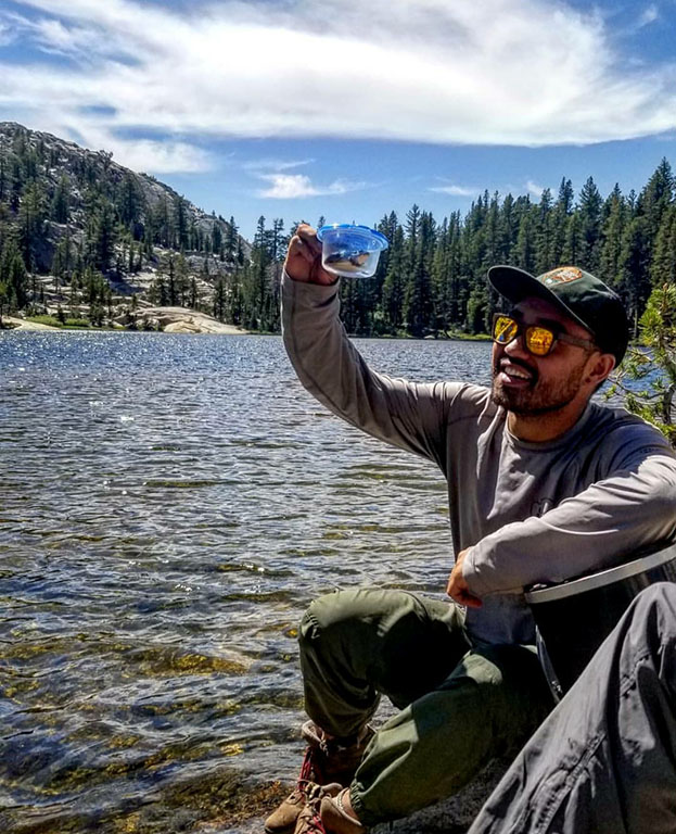 Grayson Huston holding a creature in a tub in front of a lake