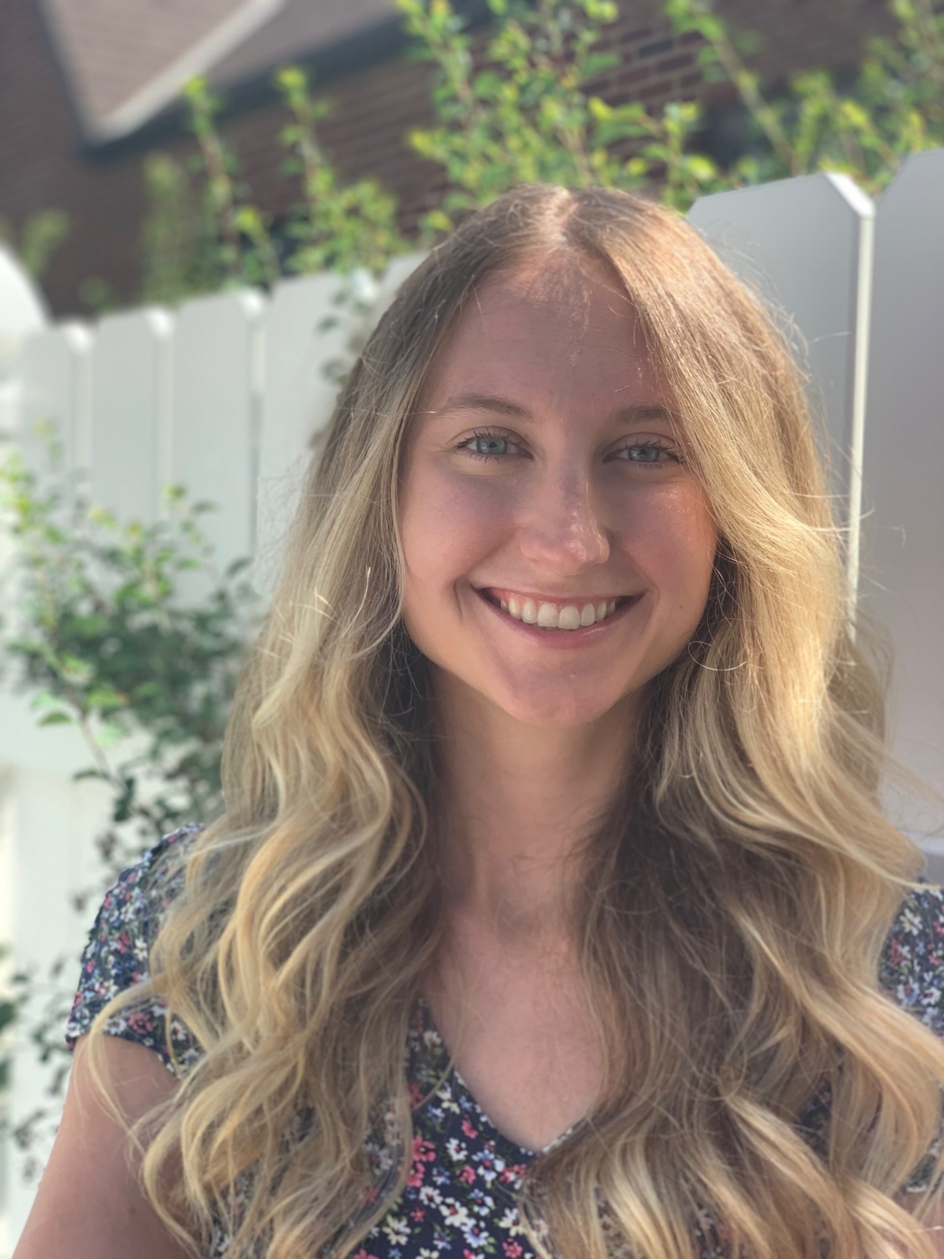 Holly White smiling in front of a fence